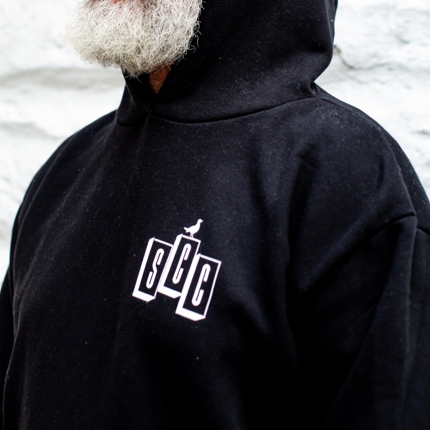 Person wearing a black hoodie with a Surf City cycles logo on the chest against a blurred background