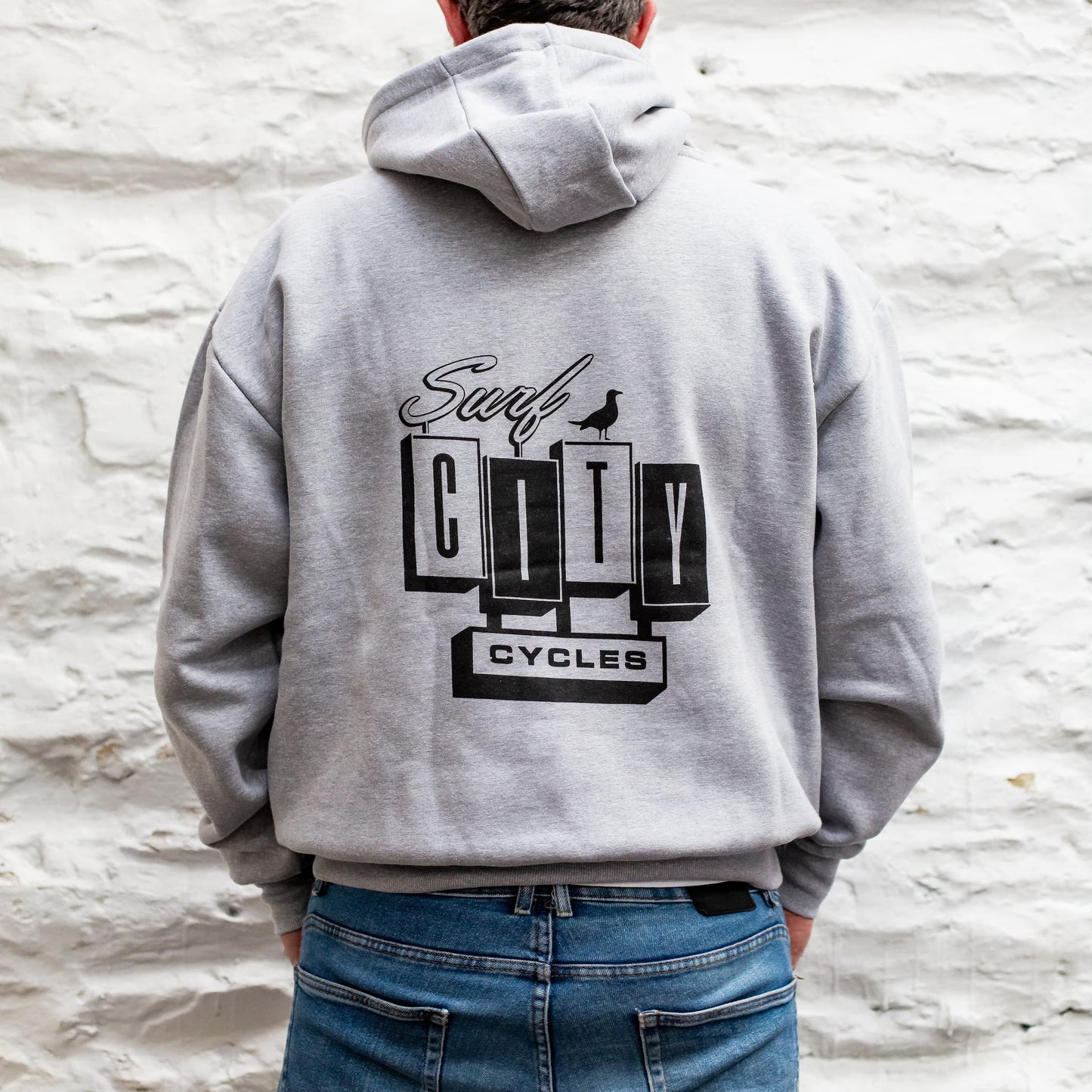 Side profile detail of the heather grey heavyweight hoodie on Andrew Pringle, showcasing the premium fabric and cuff.