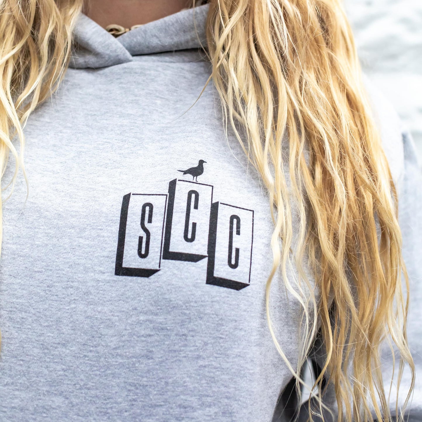 Close-up detail of the black OG logo print on the textured heather grey heavyweight cotton hoodie.