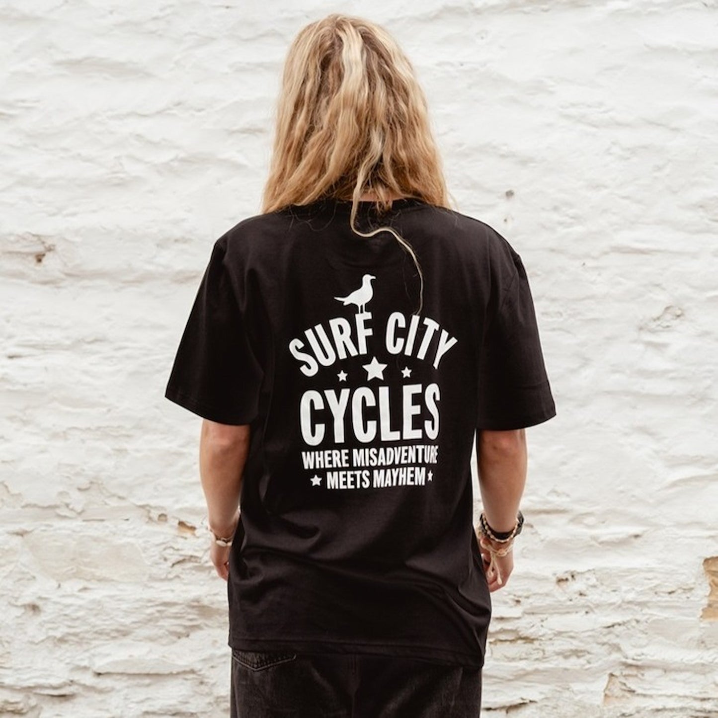 Tight detail of the white "Misadventure" skeleton rider graphic on the black crewneck sweatshirt.