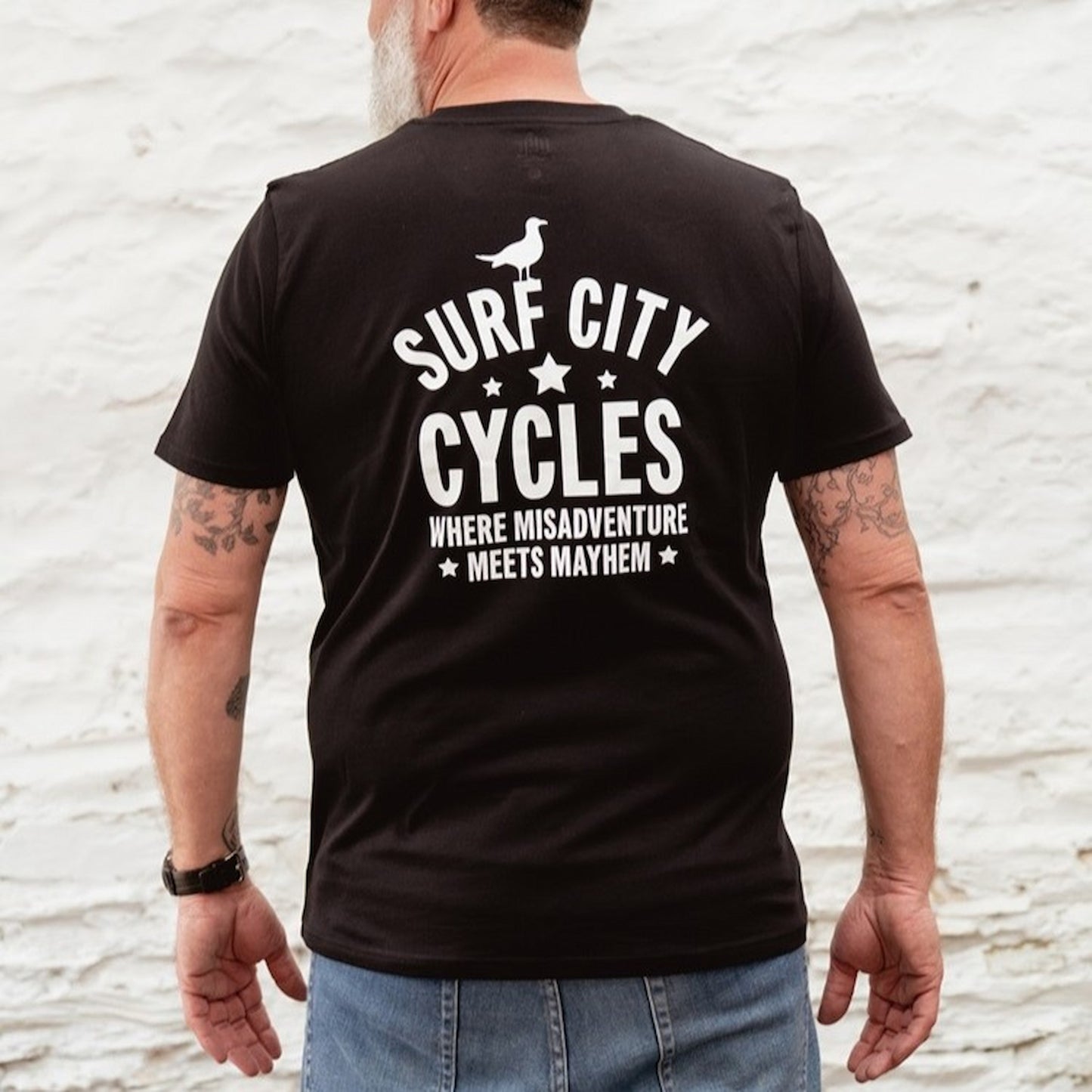 Close-up of the white screen-printed "Misadventure" skeleton motorcycle graphic on a black cotton tee.