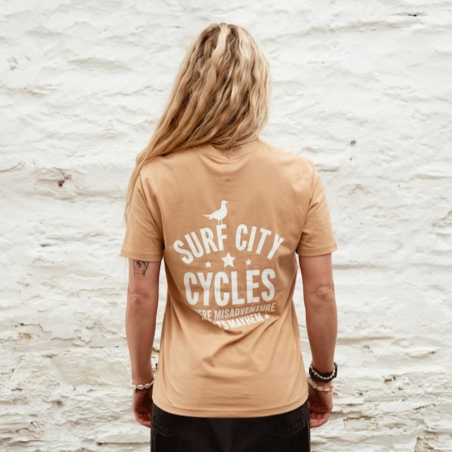 Tight detail shot of the screen-printed "Misadventure" motorcycle graphic on the latte crewneck sweatshirt.