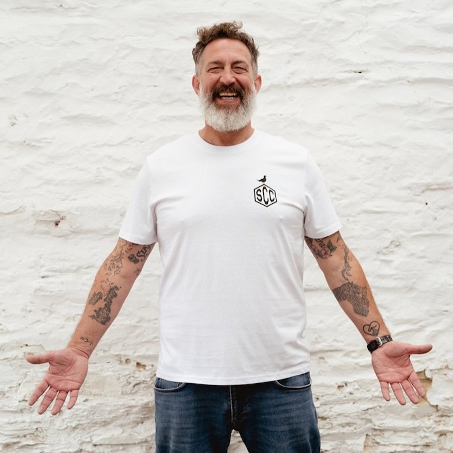 Bearded man wearing the white "Misadventure" t-shirt with a black skeleton motorcycle graphic.