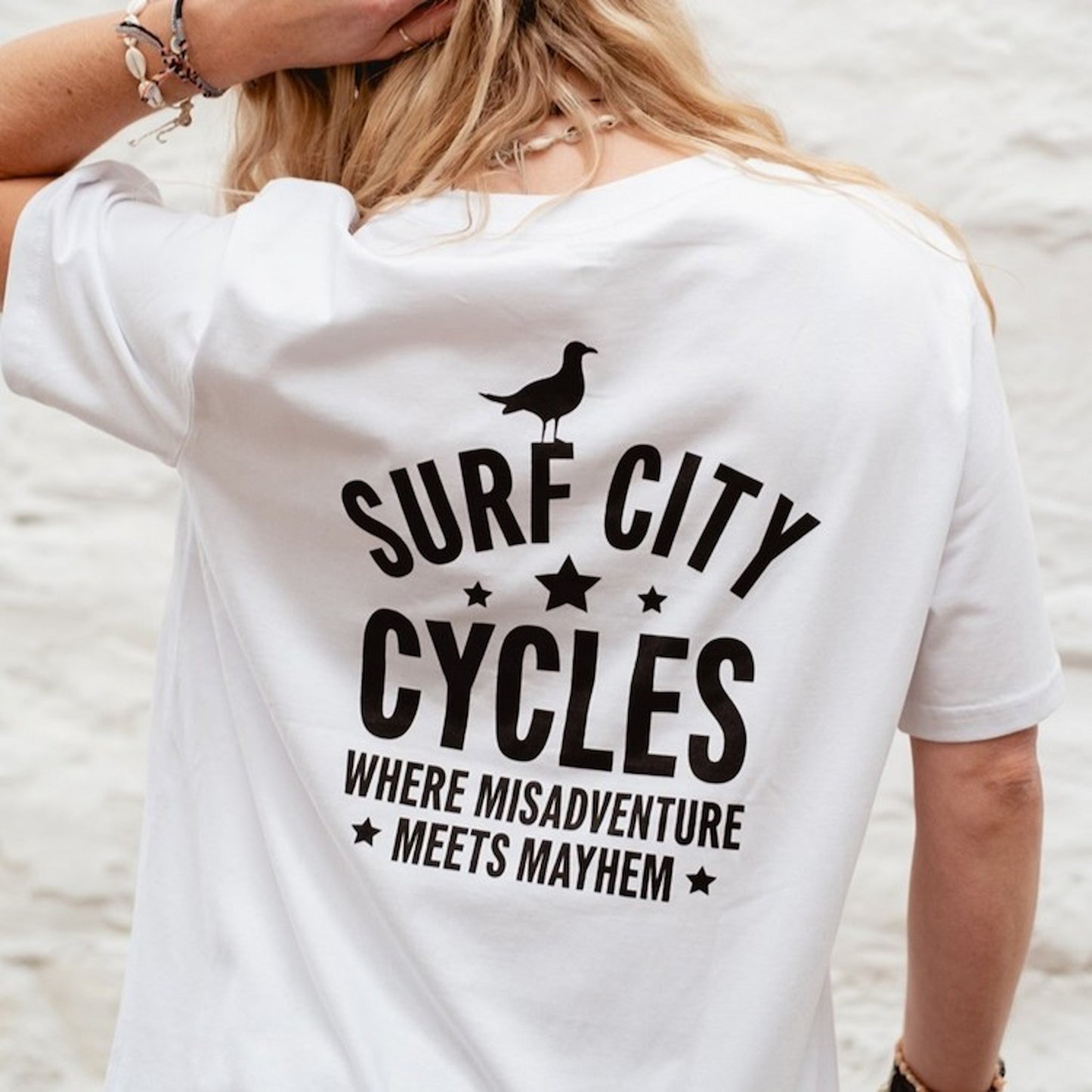 Tight detail of the black "Misadventure" motorcycle illustration on the white crewneck organic cotton t-shirt.