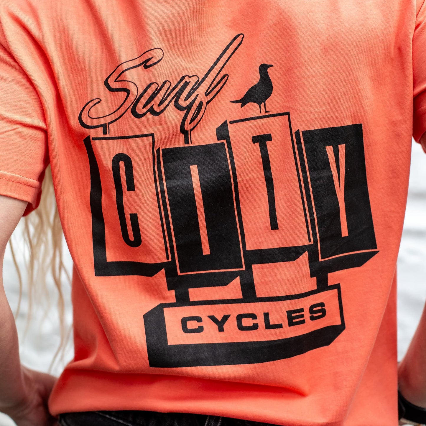Close-up of the back of the Fiesta OG Logo organic cotton tee, showing the large Surf City Cycles block logo and bird graphic.