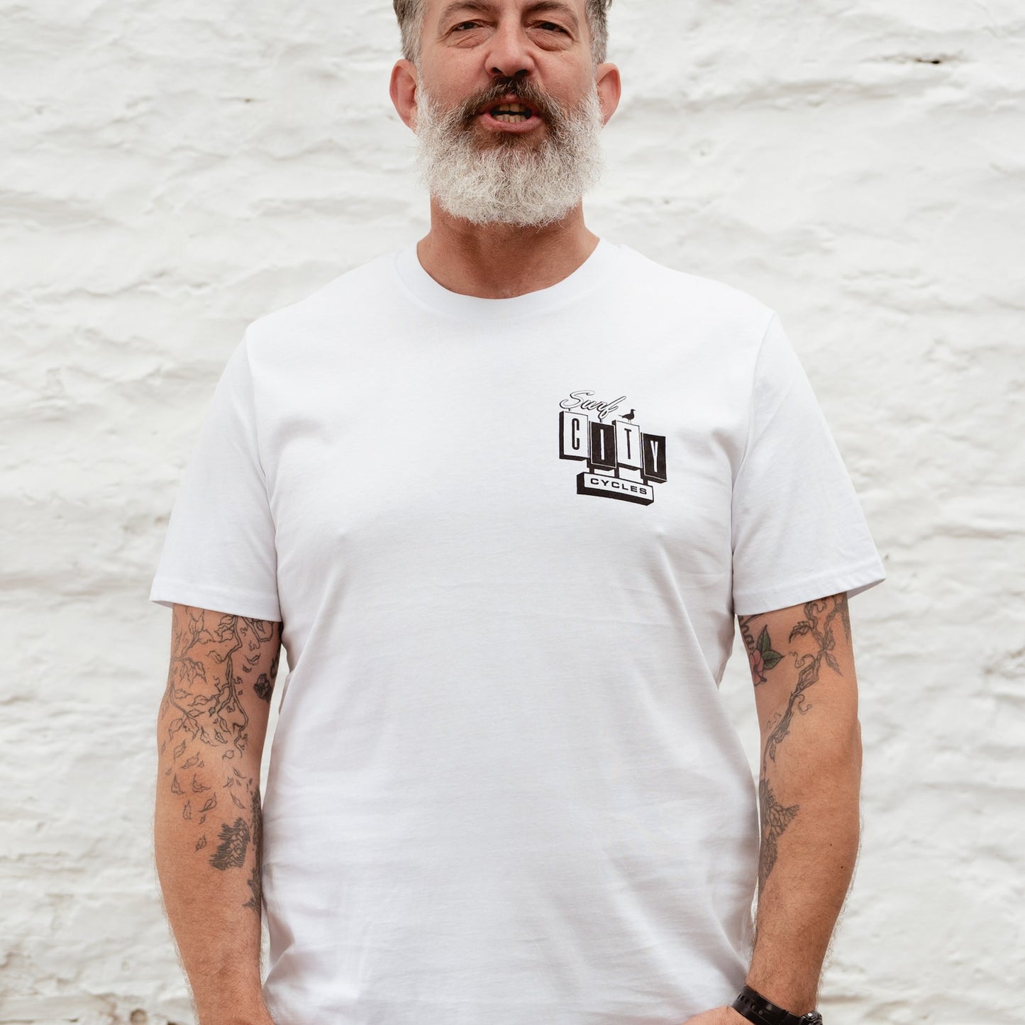 A straight-on portrait of a male model wearing the White OG Logo organic cotton tee, showcasing the chest branding and relaxed fit.