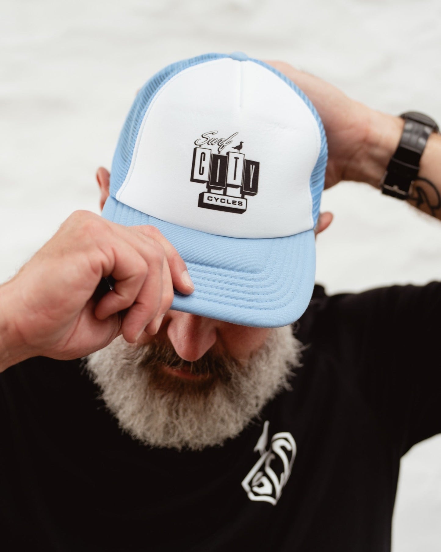 Baby blue and white OG Logo trucker cap by Surf City Cycles worn by model outdoors, lifestyle shot, unisex