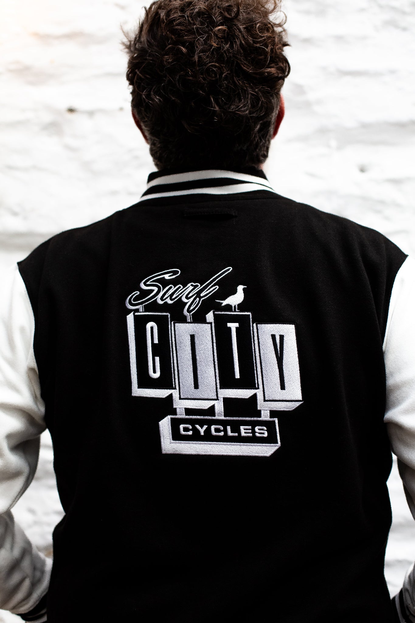 Black and cream varsity jacket by Surf City Cycles, back view, unisex