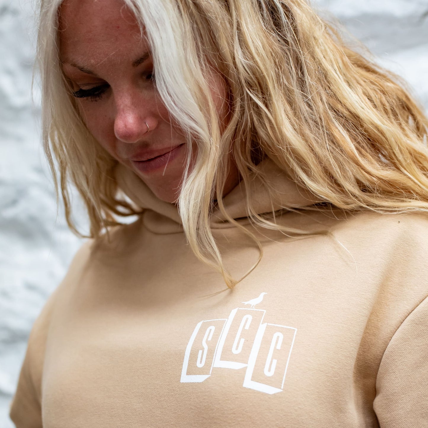 Detailed shot of the black screen-printed Surf City Cycles logo on the chest of a Desert Sand hooded sweatshirt.