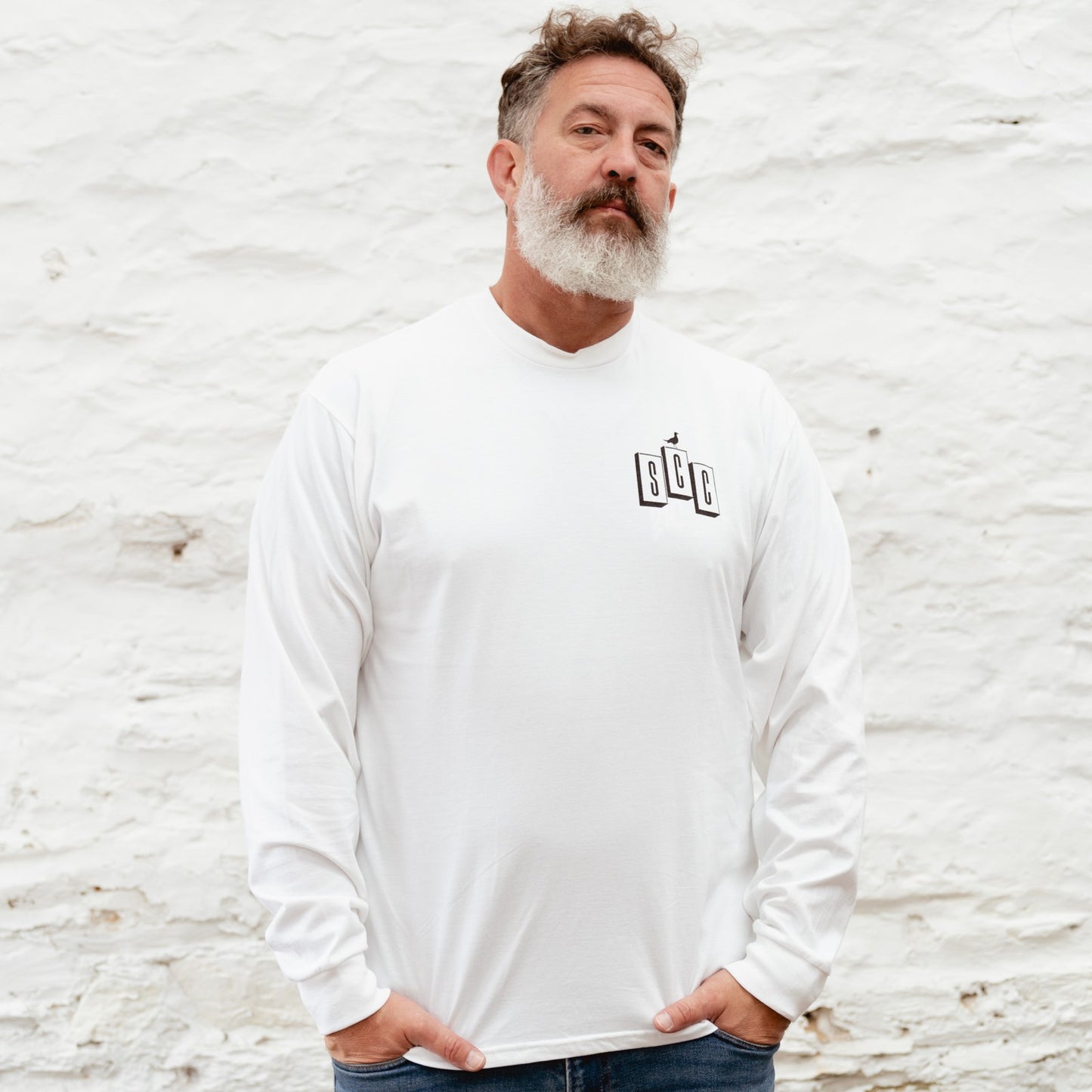 Candid workshop shot featuring the white long sleeve OG logo tee, highlighting the rugged moto-culture aesthetic.