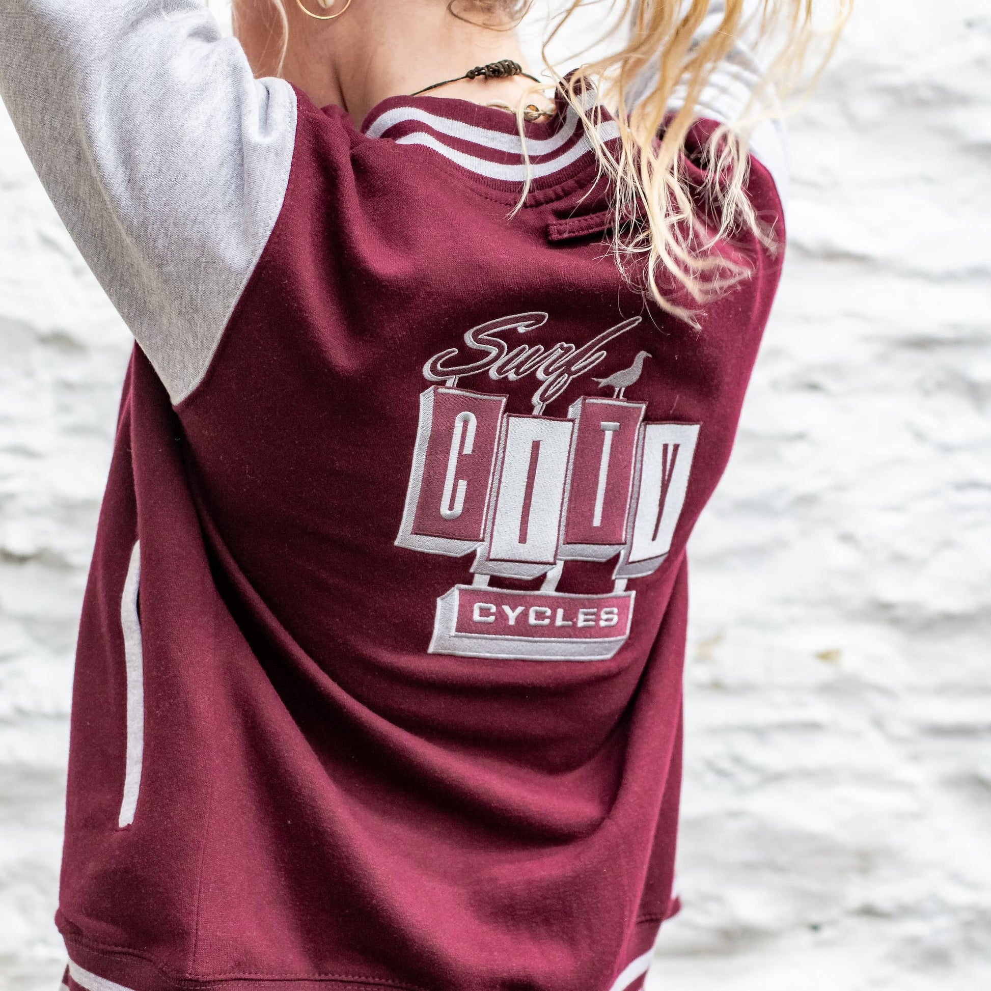 Rear view showing the back branding and grey sleeve contrast on the burgundy varsity jacket.