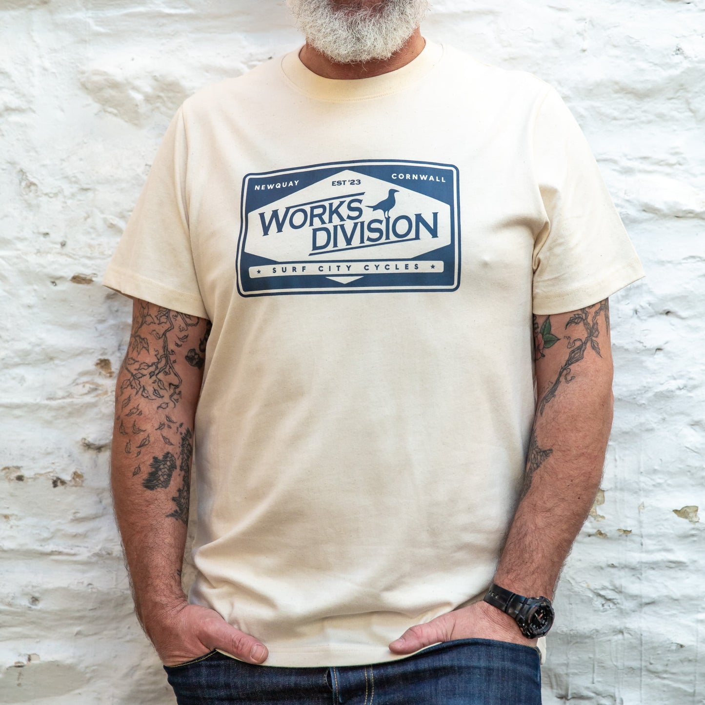 The Works Division Heavy Utility Tee in Natural, showing the relaxed fit on a tattooed male model.